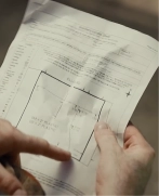Hands holding and pointing to a construction site blueprint.
