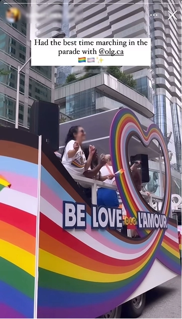 Social media post has a colourful parade float with rainbow heart and “BE LOVE L’AMOUR” sign; people onboard celebrate in front of tall city buildings.